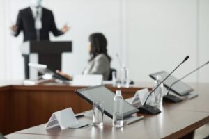 A conference room setup with tablets, microphones, and water bottles for a professional meeting.